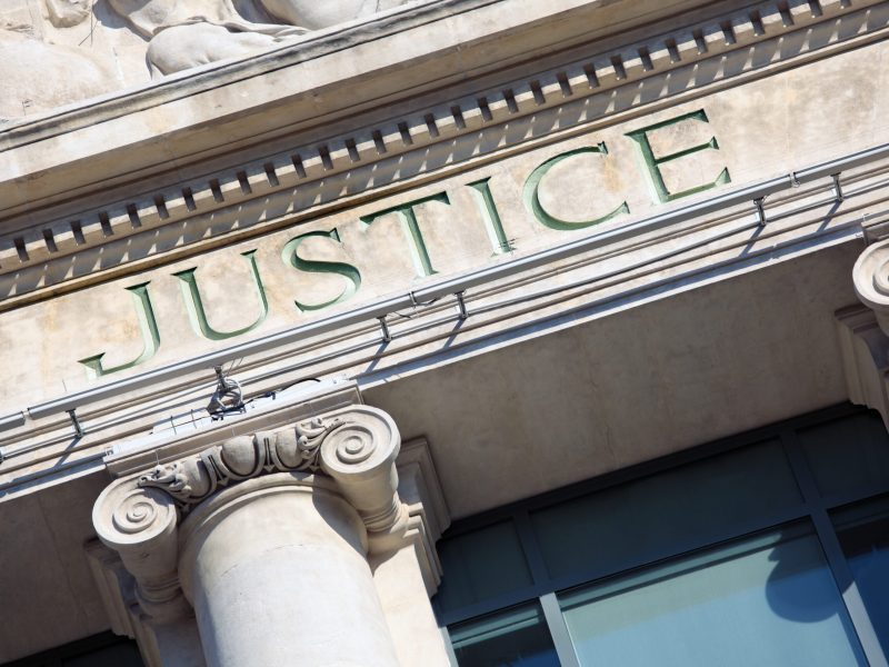 The word Justice on a Courtroom Building.